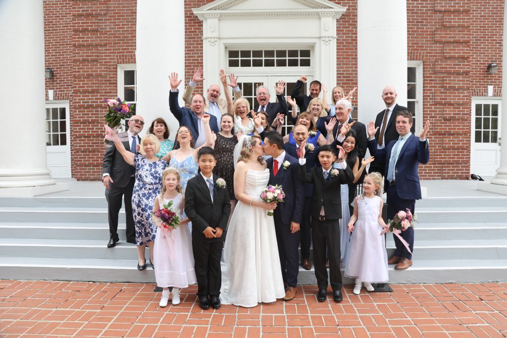 Die Hochzeitsgesellschaft und die Gäste versammeln sich vor der Kirche für ein besonderes Foto des Brautpaares mit allen Gästen