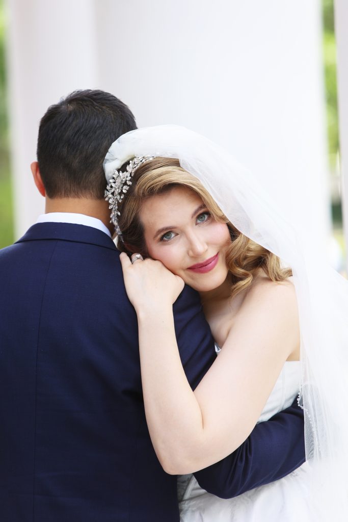 Die Braut mit Schleier lehnt sich liebevoll an die Schulter des Bräutigams