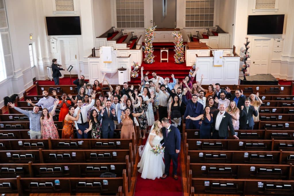 Leila and Derrick walk down the aisle together as guests cheer in celebration.