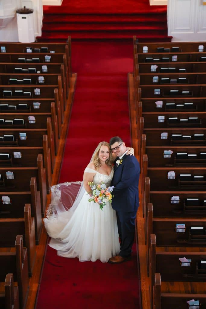 Leila and Derrick pose at the center of the red-carpeted church aisle at the First Congregational Church of Winter Park.